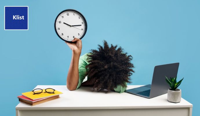 Mulher jovem com a cabeça curvada numa mesa de escritório demonstrando sinais de que sofre com a procrastinação
